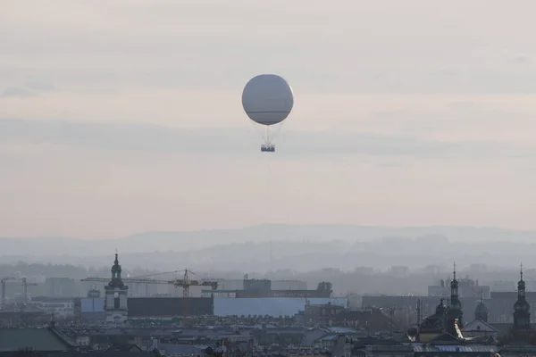 a white balloon flies over the old town in foggy weather in Krakow. attraction for tourists, flying over the city. stone jungle with a bird\'s eye view.