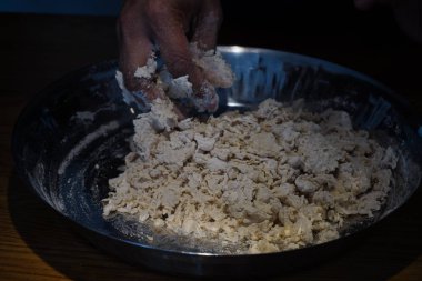 Hamuru ekmek ya da pizza için demir bir kase buğday ya da çavdar ununa yoğur. Hintli ya da Amerikalı esmer tenli ya da melez bir adamın elleri. Ev yemeği, pişirme..