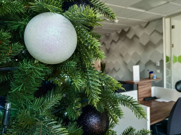 Árbol de Navidad en la oficina, creando un ambiente festivo en el lugar de trabajo. el contraste de palma y abeto, la diferencia de tradiciones y culturas en una ciudad multinacional . —  Fotos de Stock