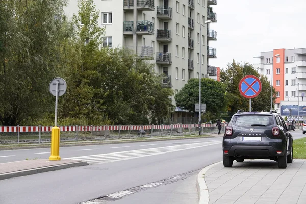 Poland, Krakow - October 4, 2019: Dark gray car dacia duster stands in front of a road sign prohibiting stopping and Parking. Parking of personal vehicles on the sidewalk, Parking on the curb, near th — Stock Photo, Image