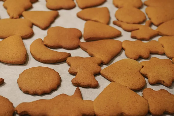 Baked brown gingerbread of different shapes on baking paper. the smell of cinnamon and ginger in the house, festive mood. homemade cookies made by hands, playing with children — Stock Photo, Image