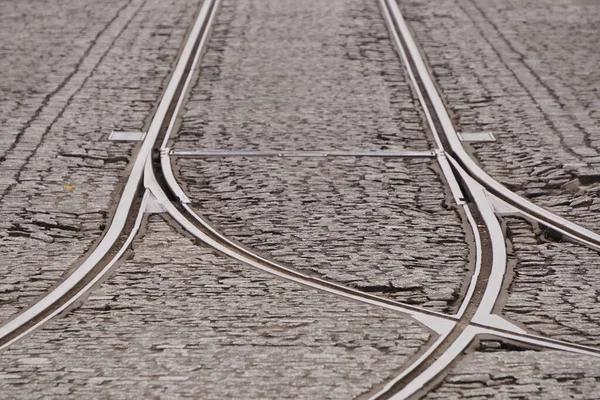 Trilhos dobrando na cidade na rua com pedras de pavimentação. rede de eléctricos, transportes públicos, comunicações urbanas. fundo screensaver, espaço de cópia para texto — Fotografia de Stock