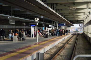 Krakow, Polonya 20.12.2019: Birçok insan modern bir tren istasyonunda treni bekliyor. İstasyonun ortasında insanları kaldıran bir gezgin var. Yolcu treni