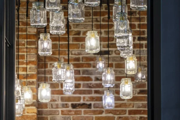 Unusual lamps made of glass jars, suspended from the ceiling by black cables. interior of a restaurant, cafe, shopping center. unusual interior solutions — Stock Photo, Image