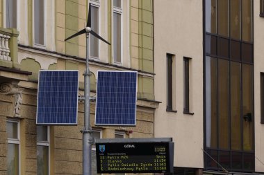 Zywiec, Krakow 01.17.2020: Şehirde gündüz binalara karşı küçük yel değirmenleri ve solapanellerle sokak elektriği. Yenilenebilir, eko veya çevre dostu ve temiz enerji kavramı.