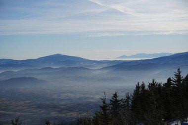 Panorama Beskid slaski. Szczyrk, Silezya bölgesindeki Skrzyczne zirvesinden Polonya 'ya sisli ve güneşli bir kış gününde dağ manzarası. Dağlar kısmen karla kaplı..