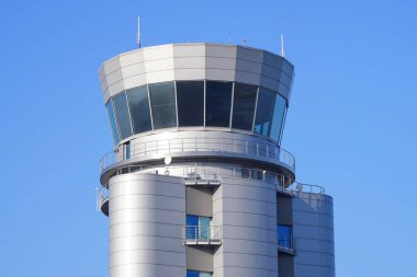 Control tower of the international airport. Aviation control room. Modern airport building, gray facade against the blue sky, large windows.