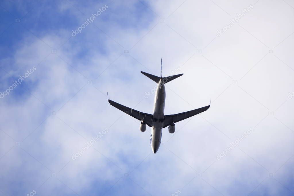 Boeing 737 in flight, bottom view, against the blue sky with clouds, bottom of the plane.