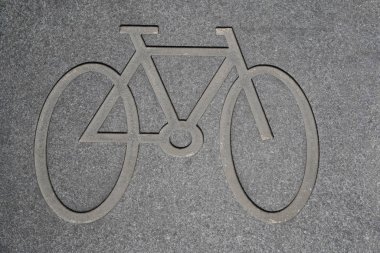 Beton yolda bisiklet sembolü var. Yol kenarındaki bisiklet şeridini işaretleyen asfaltta duran bir bisikletin piktografı. Yolda bisiklet simgesi.