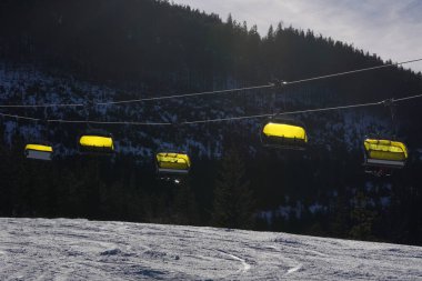 Sarı kapaklı bir taksiyle dağlarda boş bir teleferik.