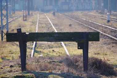 Eski istasyondaki tren için sanayi manzarası, siyah ahşap çit. Demiryolları ufkun çok ötesine uzanır güneşli bir günde, metale yansıyan
