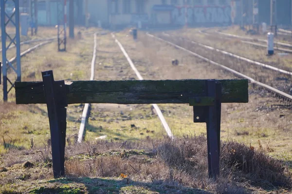 Vue industrielle de l'impasse pour le train à l'ancienne gare, clôture en bois noir. Les rails vont bien au-delà de l'horizon par une journée ensoleillée, reflétée dans le métal — Photo