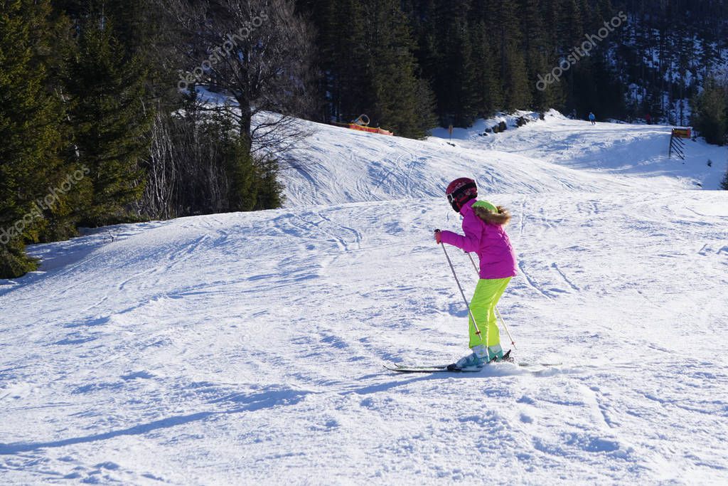 One person in bright clothes goes downhill on skis at a ski reso