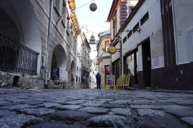 Bielsko Biala, Polonya 14.01.2020: kentte eski bir kaldırımlı sokak, reklam kafeleri ve dükkanları, uzakta bir kişi. Alt manzara, kaldırım taşlarına yakın çekim. Klasik sokak.