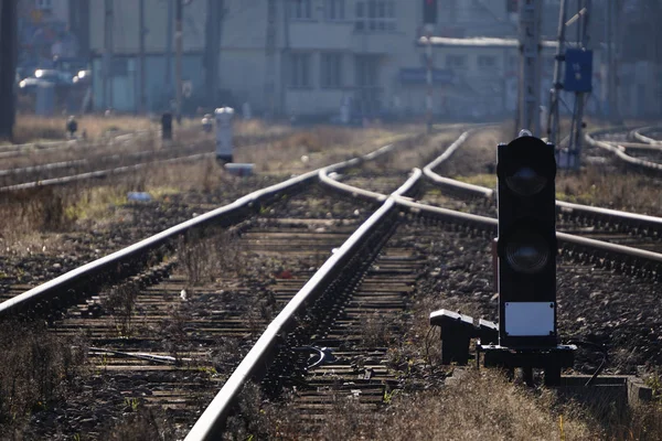 Voies ferrées, traverses et rails en bois, à l'ancienne gare par une journée ensoleillée et brumeuse. Polonais avec fils pour l'électricité, feux de circulation pour les trains, organisation de la circulation des différents trains . — Photo