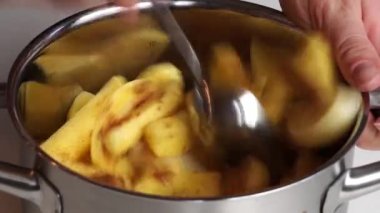 Yakın plan, bir kadın patatesleri tuz, baharat ve yağla metal bir tencerede karıştırıyor. Ev yapımı yemek.