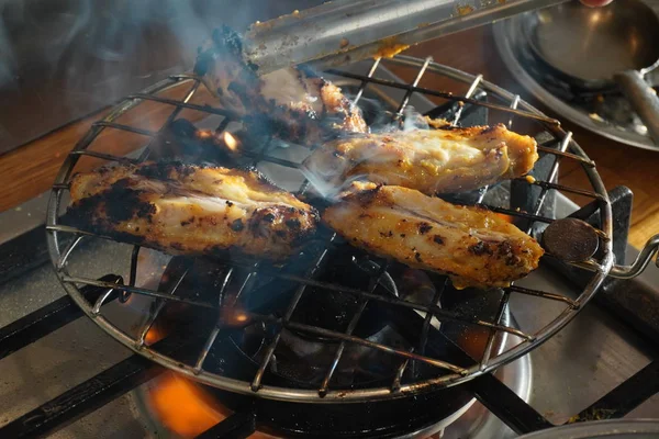 Carne di pollo su una griglia a gas in una giornata di sole. Pollo con una crosta tostata nel processo di cottura. Pezzi di pollame sono fritti sulla griglia — Foto Stock