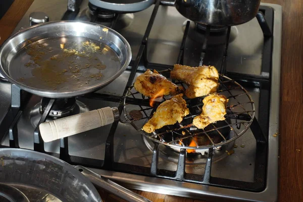 Mięso z kurczaka na grillu gazowym w słoneczny dzień. Kurczak z pieczoną skórką w procesie gotowania. Kawałki drobiu smażone są na kratce. — Zdjęcie stockowe