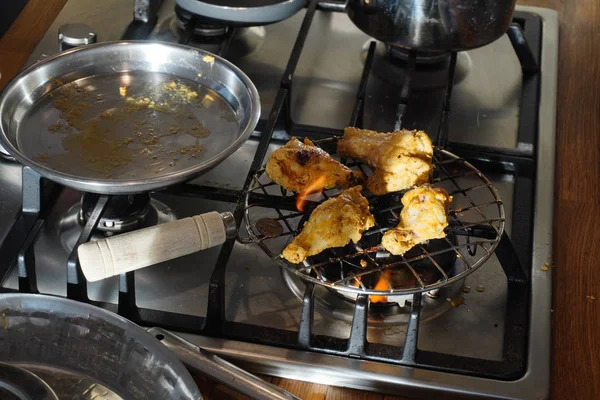 Carne di pollo su una griglia a gas in una giornata di sole. Pollo con una crosta tostata nel processo di cottura. Pezzi di pollame sono fritti sulla griglia — Foto Stock