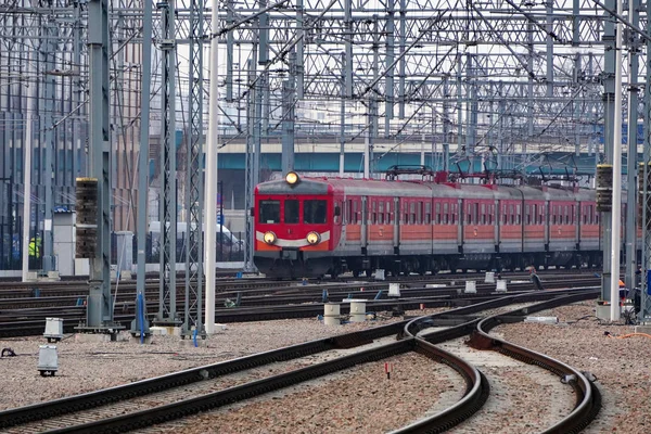 Der rote alte Elektrozug kommt am Bahnhof an Gleis, Masten und Stützen für Stromtrassen. — Stockfoto
