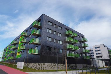 Poland, Krakow 02.16.2020: Modern multi-storey residential building with black facade finish and bright green and yellow balconies in Europe. Townhouse in modern style