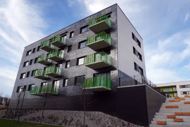 Poland, Krakow 02.16.2020: Modern multi-storey residential building with black facade finish and bright green and yellow balconies in Europe. Townhouse in modern style