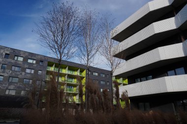 Poland, Krakow 02.16.2020: Modern multi-storey residential building with dark facade decoration and white balconies in Europe. Townhouse in a modern style on Sunny day, convenient city
