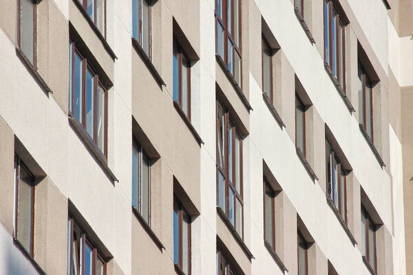 Parts of modern facade of apartment buildings made of glass and concrete with highlights on the windows in beige colors. Trends in buildings