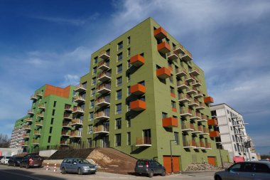Poland, Krakow 02.16.2020: Modern multi-storey residential building with black facade finish and bright green and yellow balconies in Europe. Townhouse in modern style