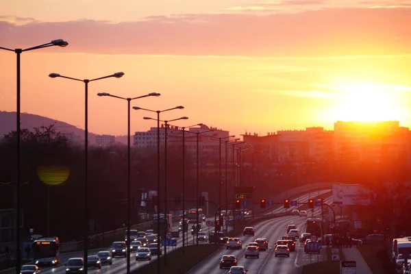 Krakow, Poland 02.18..2020: Beautiful sunset over the city. The road at sunset. Cars drive along a city street in the rays of setting sun