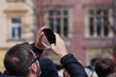 Eski bir evin arka planında siyah ekranlı cep telefonu olan turistin eli manzara ya da mimarinin fotoğrafını çekiyor. Seyahat, seyahat kavramları ve teknoloji