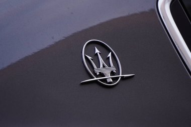 Gri bir arabanın gövdesinde Maserati logosu. Lüks İtalyan arabası. Mızrak, metal.