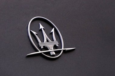 Krakow, Poland 02.15.2020: Maserati logo on the body of a gray car. Luxury Italian car. Trident, metal. clipart