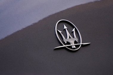Gri bir arabanın gövdesinde Maserati logosu. Lüks İtalyan arabası. Mızrak, metal.