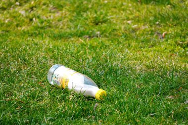 Krakow, Polonya 10.03.2020: Yeşil çimlerin üzerinde atılmış bir süt şişesi. Çevre kirliliği. Plastik atıkların geri dönüşümü. Plastik çöp.