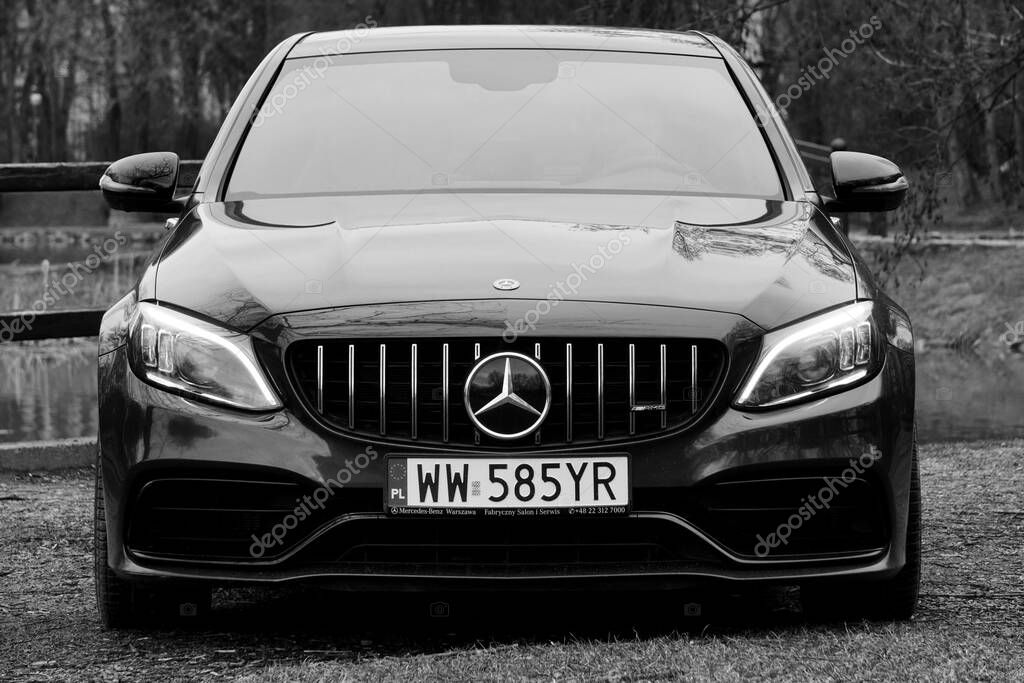 Krakow, Poland 19.02.2020: Black car Mercedes-benz C-class C63 AMG W205 luxury sport sedan, parking in city park. Detail front view of cars.