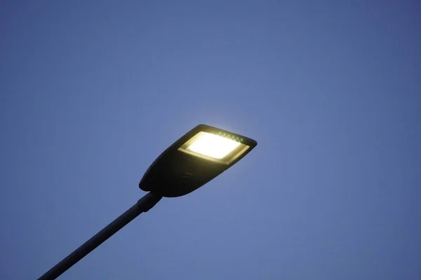 Lighting mast with lantern on a city street during the day. Lighting of roads and streets, stadiums against the blue sky.