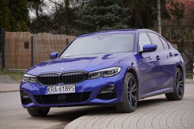 Krakow, Polonya 22.03.2020: Mavi araba BMW 3 G20 lüks Alman sedanı, şehir parkına park ediyor. Arabaların ön görüntüsünü detaylandır. Bir yerleşim bölgesindeki kaldırıma yasa dışı park edilmiş bir araba. Trafik ihlalleri