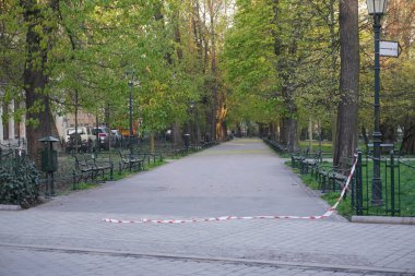 Karantina ve koronavirüs salgını sırasında Polonya, Krakow ve Bolluk Bahçeleri 'ndeki ziyaretçi park ve ormanlarına uygulanan kısıtlamaların kaldırılması. Bariyer bandı yırtılmış ve yolda duruyor. Sosyal uzaklık