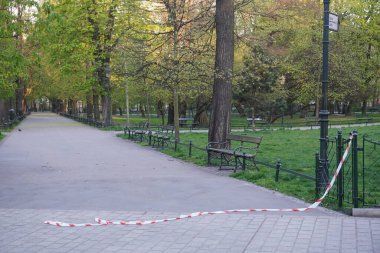 Polonya, Cracow 20.04.20: Karantina ve koronavirüs salgını sırasında ziyaret edilen park ve ormanlara uygulanan kısıtlamaların kaldırılması. Bariyer bandı yırtılmış ve yolda duruyor. Sosyal uzaklık