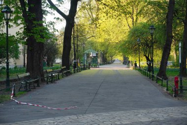 Karantina ve koronavirüs salgını sırasında Polonya, Krakow ve Bolluk Bahçeleri 'ndeki ziyaretçi park ve ormanlarına uygulanan kısıtlamaların kaldırılması. Bariyer bandı yırtılmış ve yolda duruyor. Sosyal uzaklık