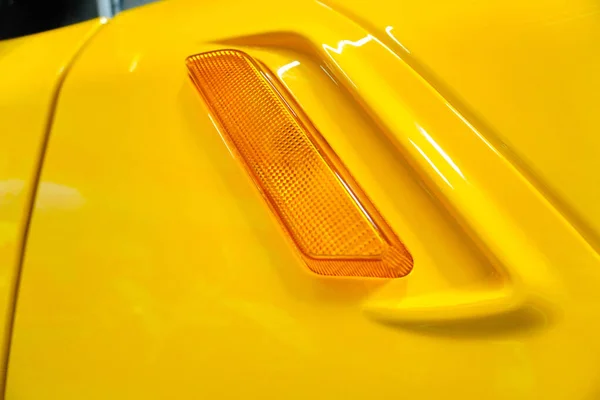 Reflective element on the body of a yellow car. Turn signal on a yellow car