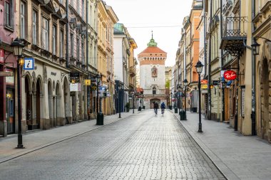 Cracow, Polonya 20.04.2020: İki bisikletçi Florianska caddesindeki eski şehrin merkezinde bisiklet sürüyor. Coronavirus salgını sırasında boş bir sabah şehri. Turist olmayan boş bir şehir. Virüs yüzünden popüler bir spor.