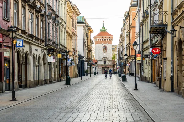 Cracow, Polonya 20.04.2020: İki bisikletçi Florianska caddesindeki eski şehrin merkezinde bisiklet sürüyor. Coronavirus salgını sırasında boş bir sabah şehri. Turist olmayan boş bir şehir. Virüs yüzünden popüler bir spor.