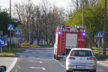 Krakow, Polonya 22.04.2020: yanıp sönen ışıkları olan bir itfaiye kamyonu şehrin sokaklarında insanlara yardım ediyor, yangın veya kurtarma ekiplerine yardım ediyor. Acil bir durumu atla, yol kuralları.