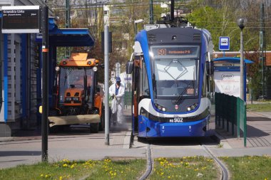 Krakow, Polonya 23.04.2020: Koronavirüs pandemiği sırasında otobüslerin ve tramvayların kirlenmesinden, bakterilerden ve virüslerden arındırılması. Koruyucu giysiler giyen erkekler toplu taşıma araçlarını ve caddeleri antiseptikle yıkıyor