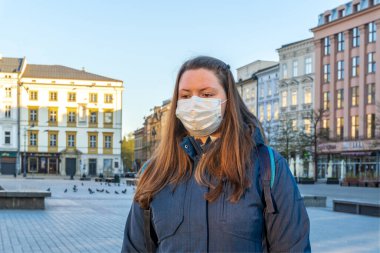 Üzgün ve hayal kırıklığına uğramış tıbbi maskeli bir kadın boş eski şehir Krakow, Polonya 'da yürüyor. Coronavirüs enfeksiyonu nedeniyle şehir merkezinde turist ya da insan yok..
