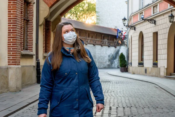 woman in medical mask walks in empty old city Krakow, Poland. No people or tourists in the city center due to coronavirus infection.