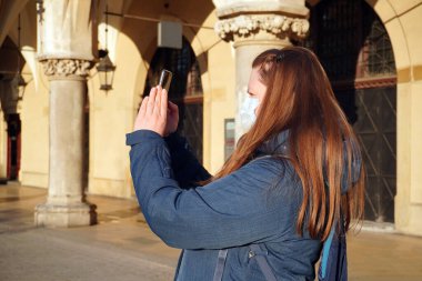 Tıbbi maskeli kadın boş eski şehir Krakow, Polonya 'da yürüyor. Coronavirüs enfeksiyonu nedeniyle şehir merkezinde turist ya da insan yok..