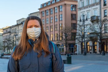 Tıbbi maskeli kadın boş eski şehir Krakow, Polonya 'da yürüyor. Coronavirüs enfeksiyonu nedeniyle şehir merkezinde turist ya da insan yok..